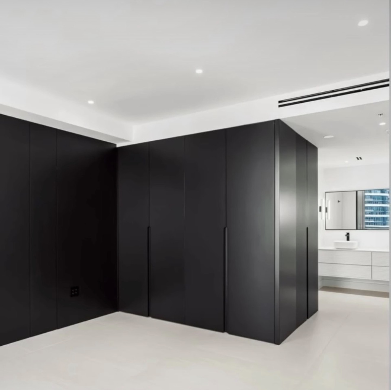 Matte black wardrobe wall wrapping into a white bathroom
