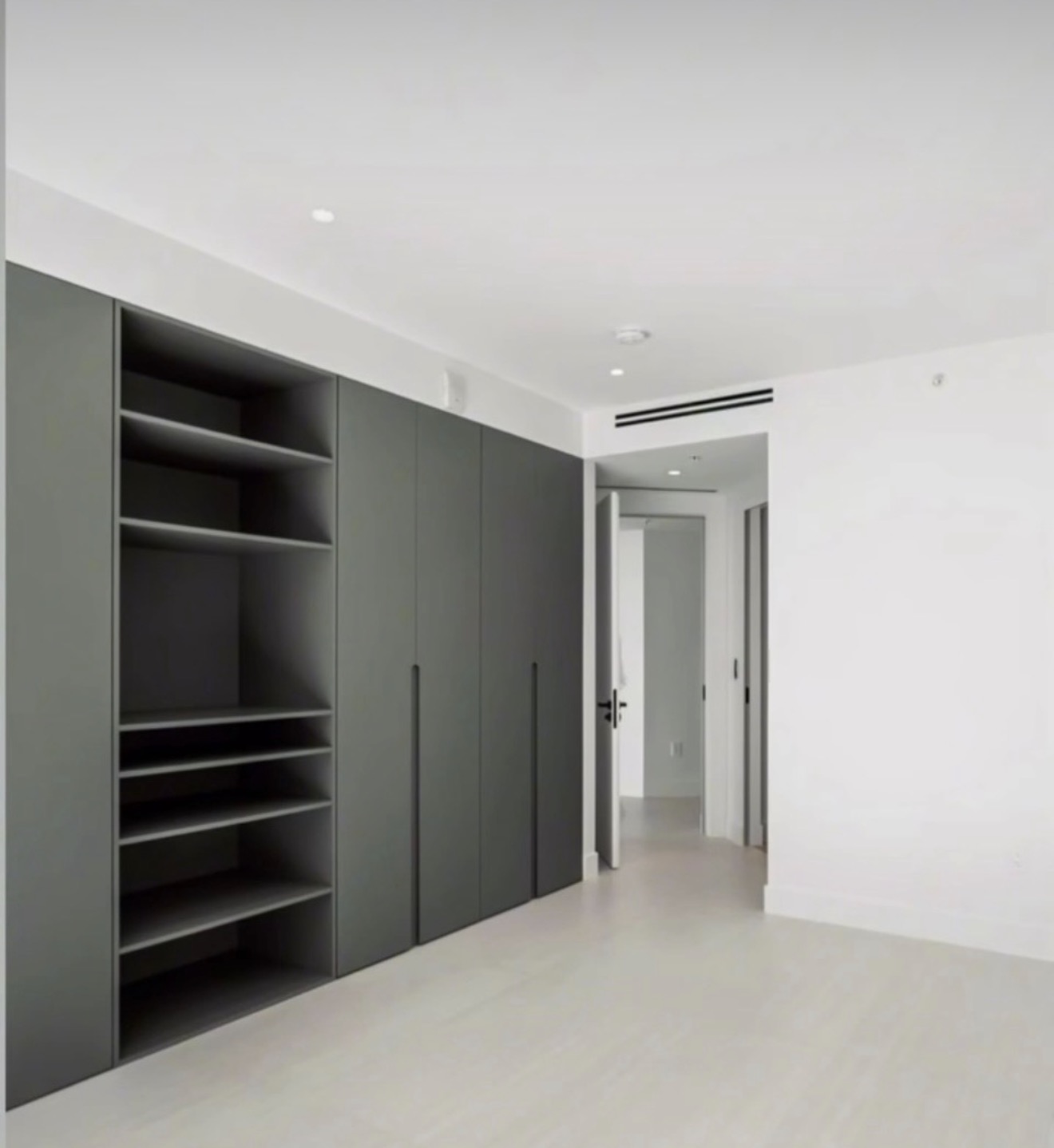 Sage-green wardrobe wall with tall handleless doors and open display shelving
