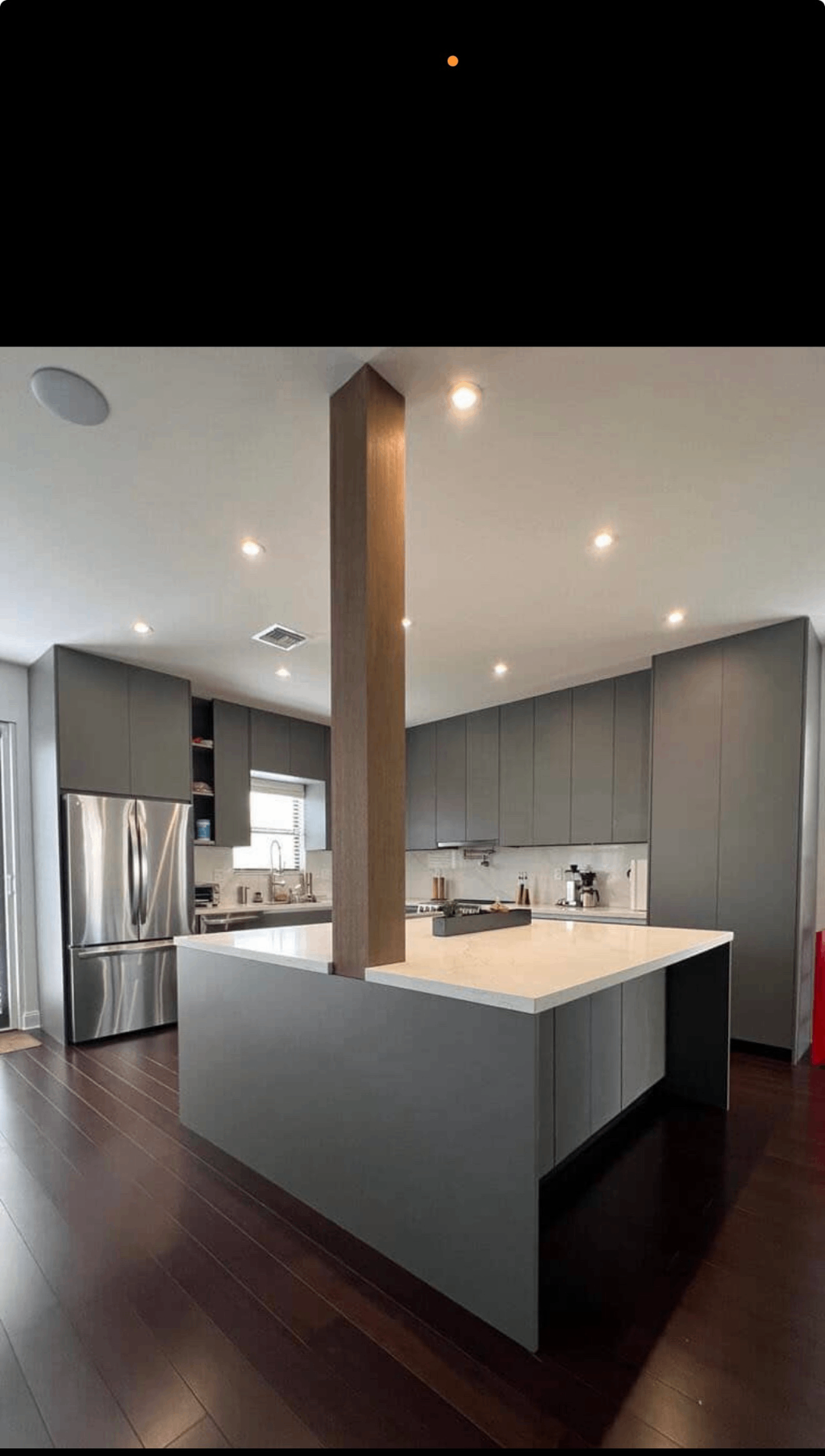 Matte gray kitchen with waterfall island and oak-clad structural column
