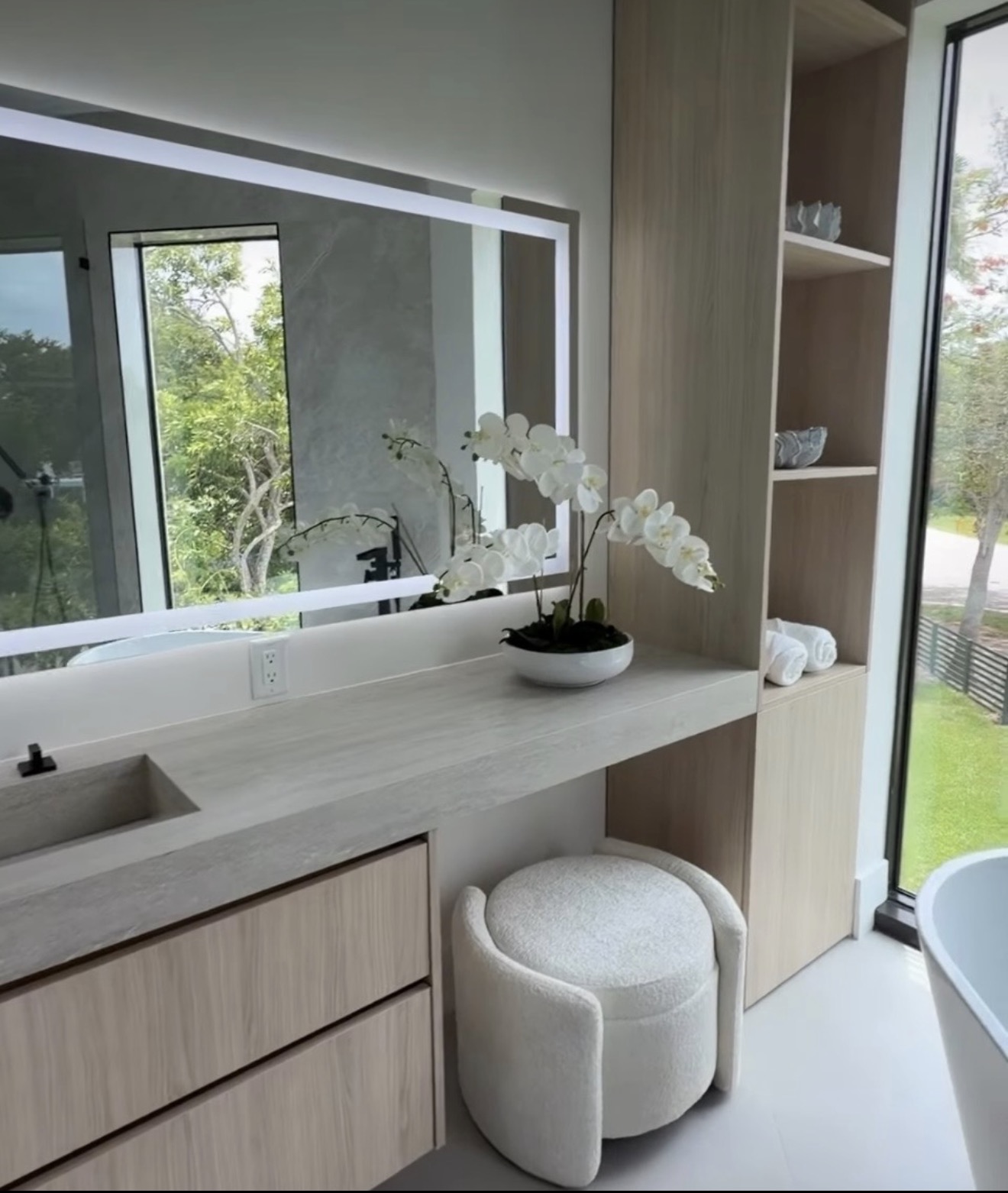 Primary bath vanity with backlit mirror, oak millwork and freestanding tub