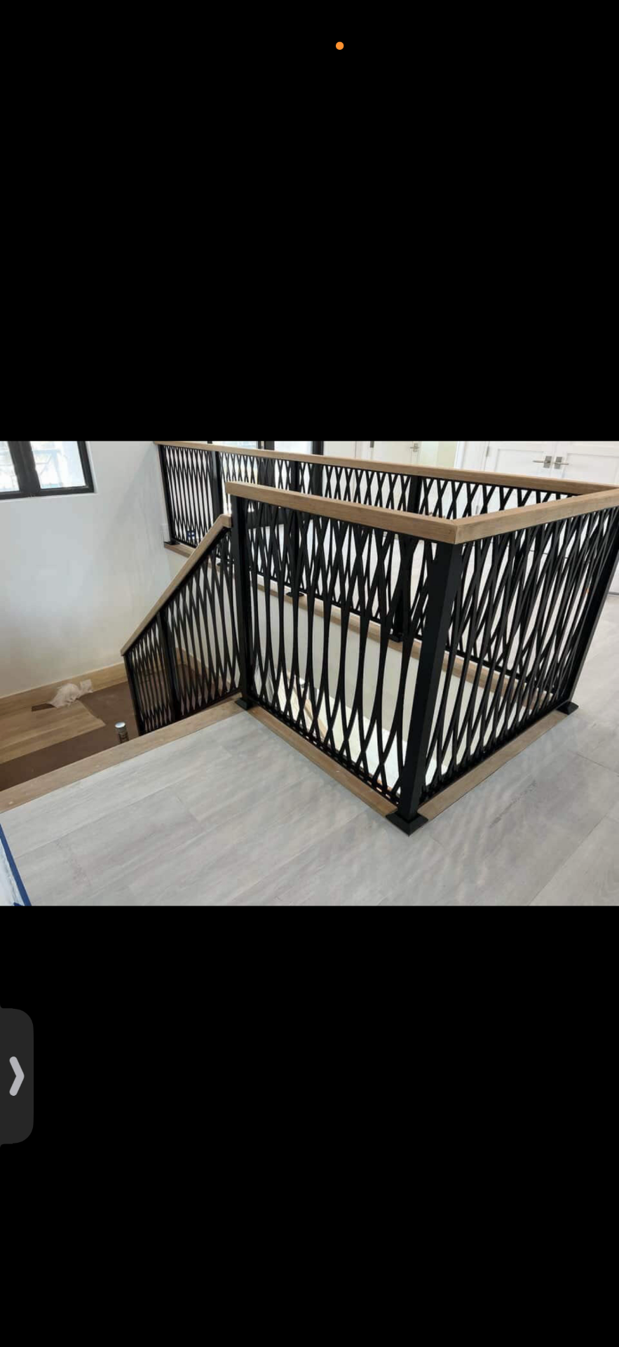 Detail of custom X-pattern black steel railing with oak cap